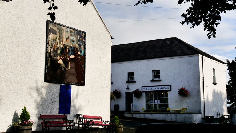 A photograph which features a mural on the side of Mary McBride's Bar, as well as The Village Tearooms café and restaurant in Cushendun, Co Antrim in Northern Ireland.